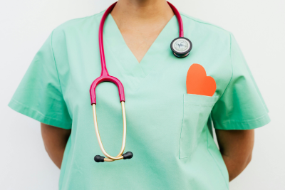 A healthcare professional in green scrubs with a stethoscope and a heart emblem, representing federal health coverage.