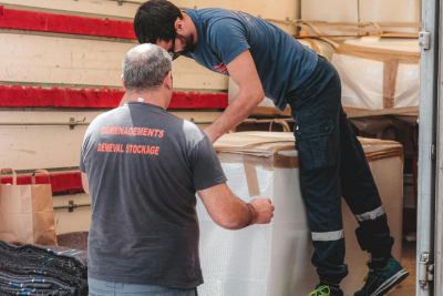 Two postal workers handling packages in a warehouse, illustrating the physical demands relevant to the Postal Disability Program.