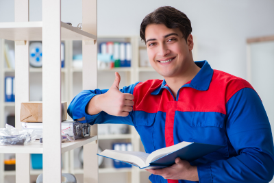 A postal worker in a blue uniform with a pixelated face stands in an office, giving a thumbs-up while holding an open book, possibly referencing the postal service retirement blue book.