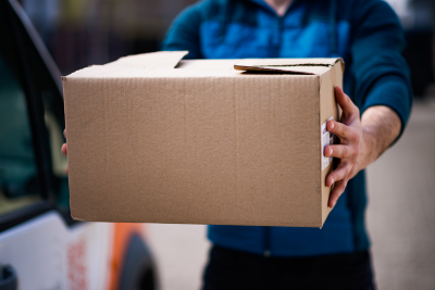 Postal worker holding a package, representing USPS short-term disability insurance support and security.