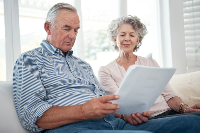 Senior couple reviewing USPS disability retirement documents at home.